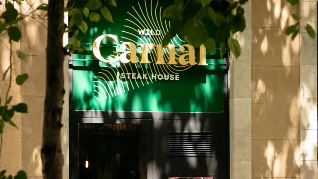 Calles comerciales iluminadas por Navidad cerca de Carnal Steakhouse, con tiendas y ambiente festivo