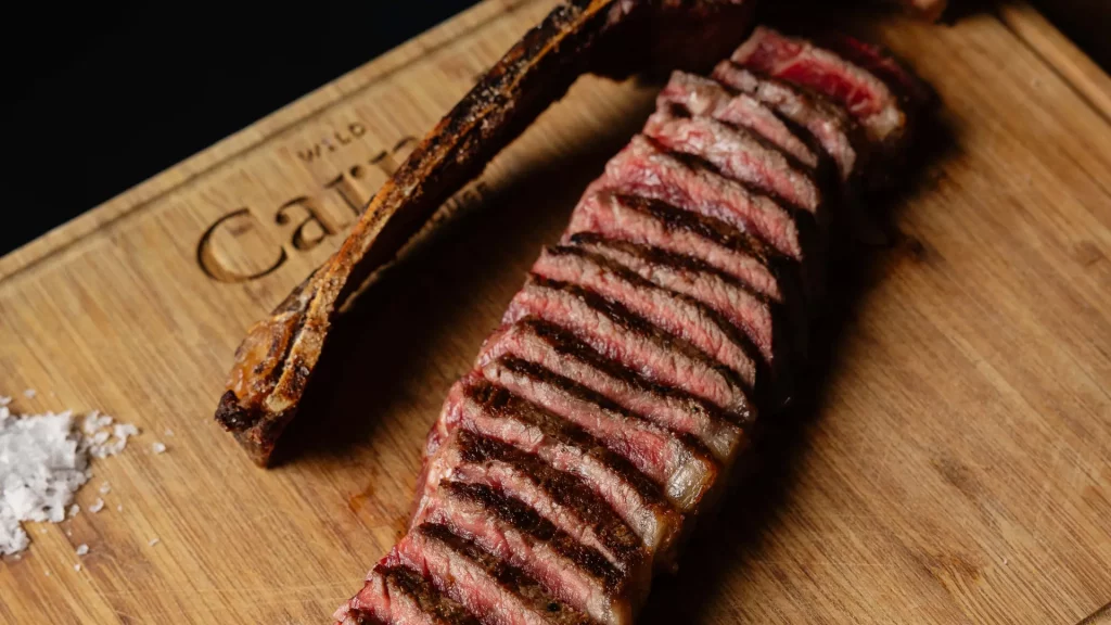 Tres cortes de carne a la brasa sobre tabla de madera: entrecot, chuletón y Wagyu, en Carnal Steak House Barcelona
